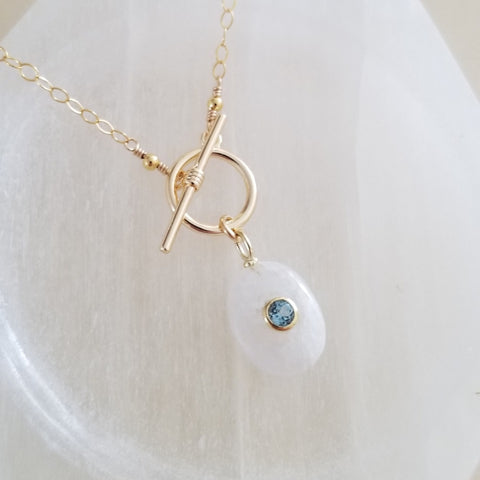 Handmade gold chain necklace with front toggle clasp, featuring a shimmering moonstone pendant and faceted blue topaz drop, elegant gemstone jewelry for everyday wear or special occasions.