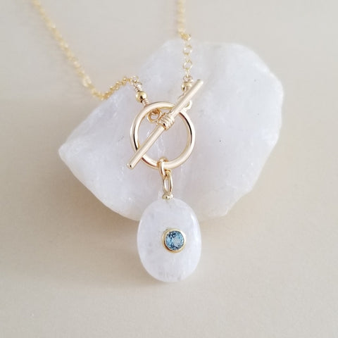 Handmade gold chain necklace with front toggle clasp, featuring a shimmering moonstone pendant and faceted blue topaz drop, elegant gemstone jewelry for everyday wear or special occasions.