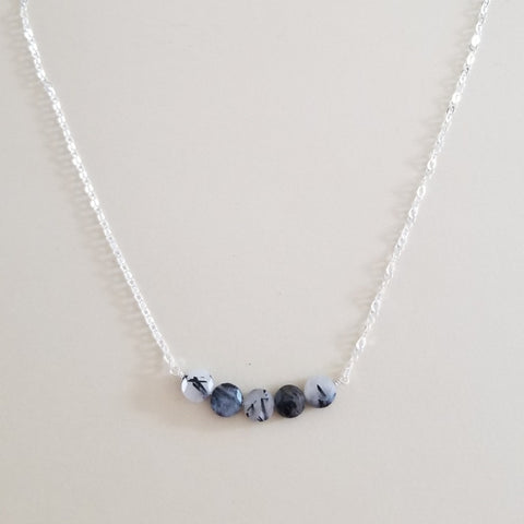 Elegant necklace featuring a row of black rutilated quartz gemstones on a delicate chain, modern crystal jewelry with natural needle-like patterns. Gift for her