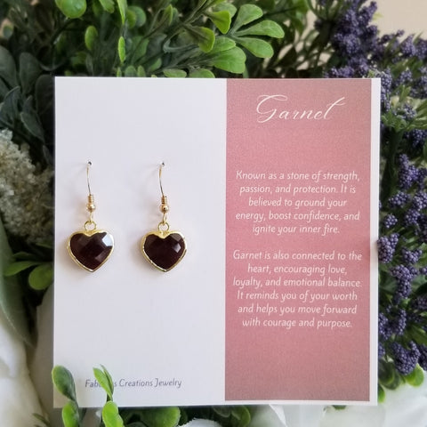 Heart-shaped garnet earrings on a card with descriptive text against a floral background