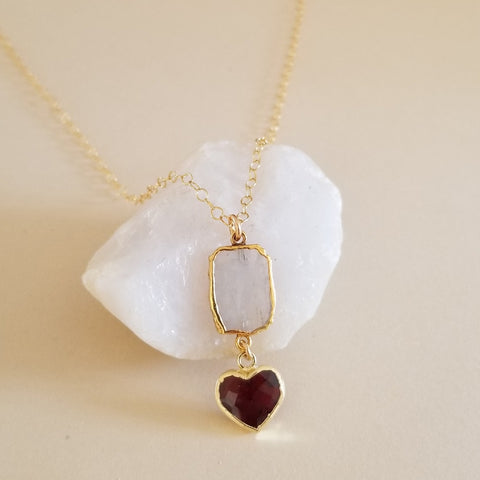 Handmade moonstone and garnet heart pendant necklace displayed on a gold filled chain. Boho stone necklace for women.