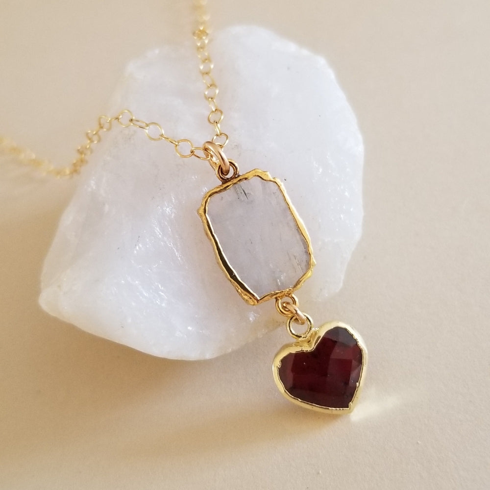 Handmade moonstone and garnet heart pendant necklace displayed on a gold filled chain.