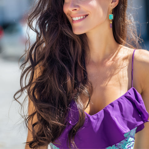Woman wearing a purple top with a blurred background wearing Turquoise and Amethyst earrings
